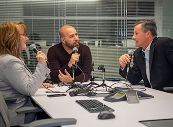 Three people sitting in a conference room. 